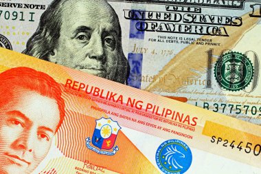 Turuncu bir makroda bir Amerikan mavi yüz dolarlık banknot ve yirmi Pezosu notla Filipino görüntüsünü yakından