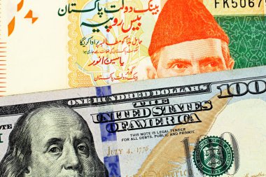 Pakistan 'dan yirmi Rupisi banka notu bir makro görüntü bir Amerikan 100 dolarlık fatura ile yakın