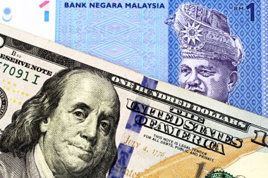 A blue one ringgit bank note from Malaysia with an American one hundred dollar bill in macro