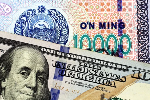 来自乌兹别克斯坦的一张一万索姆钞票的近景图片是在宏观上以一张100美元的美国钞票收场 — 图库照片