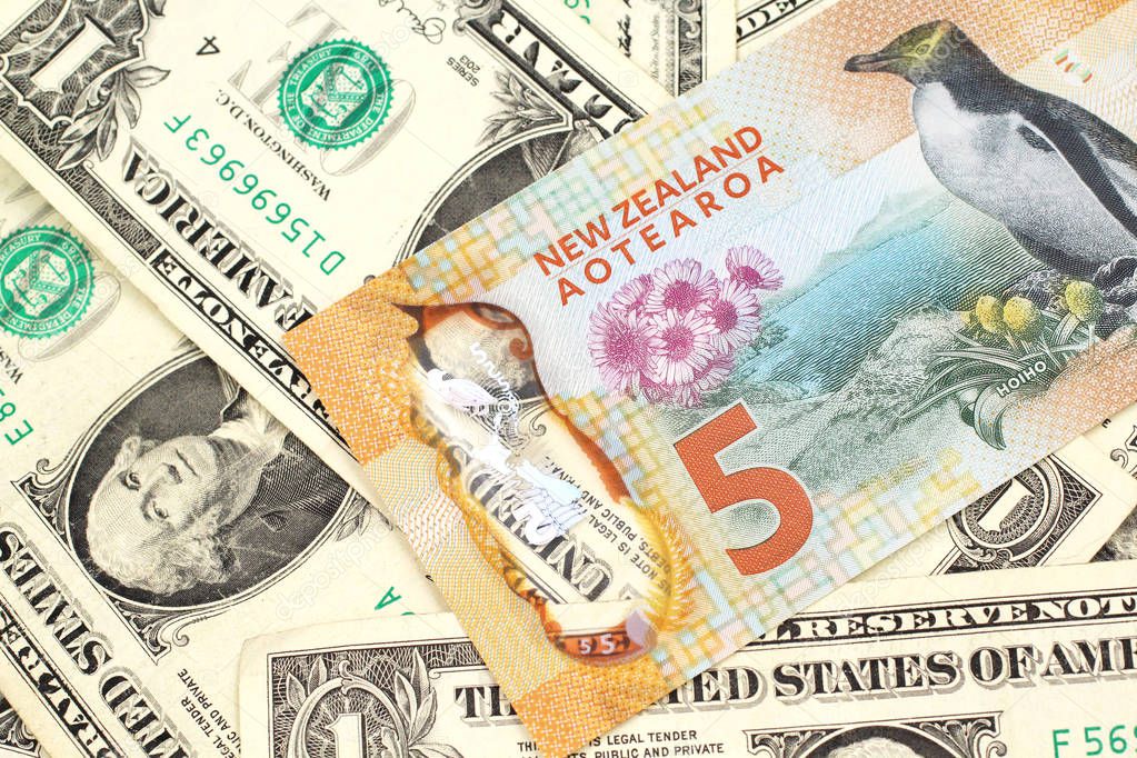 A close up image of a New Zealand five dollar bill with United States one dollar bills in macro