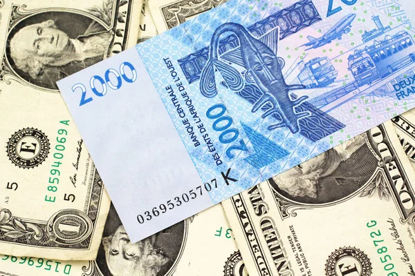一张蓝色 西非法郎纸币的特写图像 在宏上印有美国一美元钞票的背景 — 图库照片