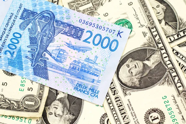 一张蓝色 西非法郎纸币的特写图像 在宏上印有美国一美元钞票的背景 — 图库照片