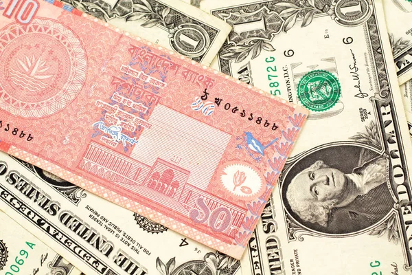 一张来自孟加拉国的红色 十塔卡钞的特写图片 这张钞票上一张美国一美元钞票在宏上 — 图库照片