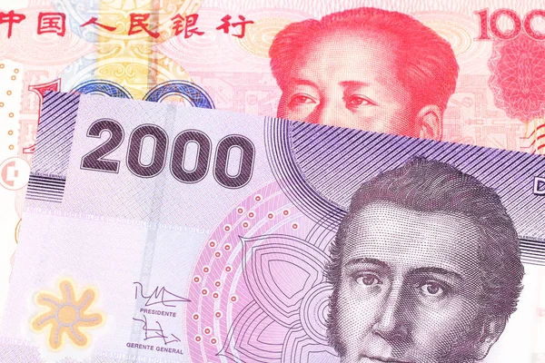 A purple two thousand peso bank note from Chile with a red, Chinese one hundred yuan bank note close up in macro