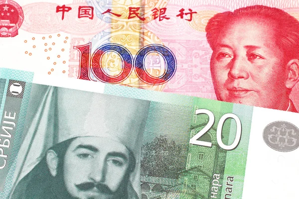 A twenty Serbian dinar bank note, close up in macro with a red Chinese one hundred yuan renminbi bank note