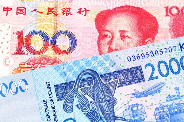 100の中国人民元紙幣をマクロで持つ青い西アフリカのフラン紙幣のクローズアップ画像 — ストック写真