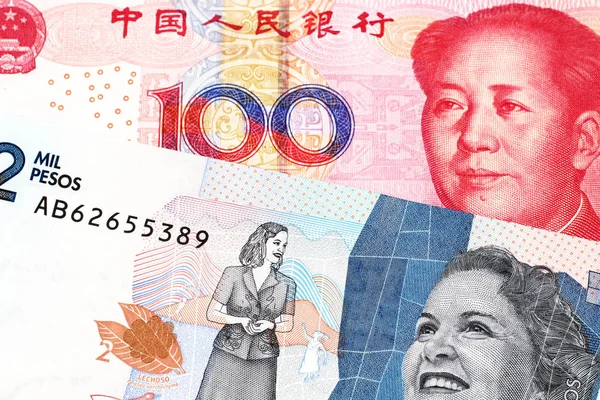 A red, Chinese one hundred yuan renminbi bank note with a blue two thousand peso note from Colombia close up in macro