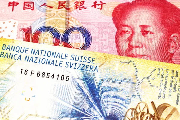 A yellow, ten Swiss franc note with a red, one hundred yuan renminbi bank note from the People\'s Republic of China