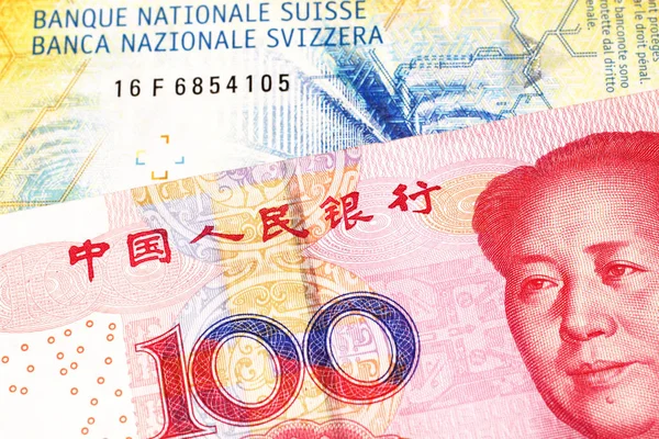 A yellow, ten Swiss franc note with a red, one hundred yuan renminbi bank note from the People\'s Republic of China