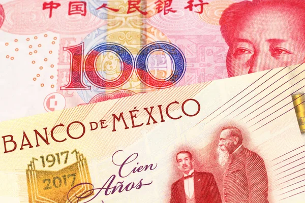 A one hundred Mexican peso bill, shot in macro with a red one hundred yuan bank note from the People\'s Republic of China