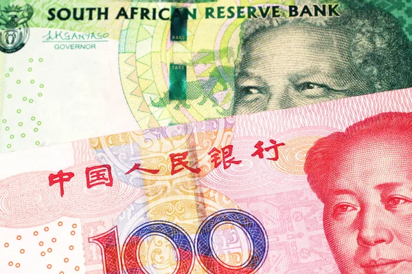 A green ten rand note from South Africa close up in macro with a red one hundred yuan renminbi bank note from the People\'s Republic of China