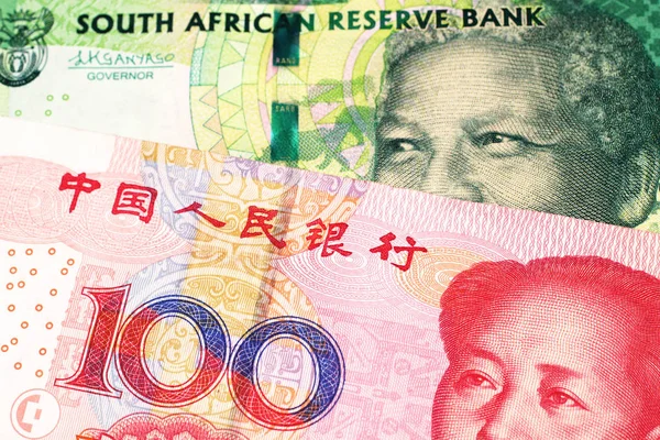 A green ten rand note from South Africa close up in macro with a red one hundred yuan renminbi bank note from the People\'s Republic of China