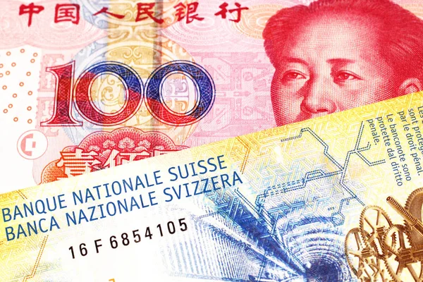 A yellow, ten Swiss franc note with a red, one hundred yuan renminbi bank note from the People\'s Republic of China