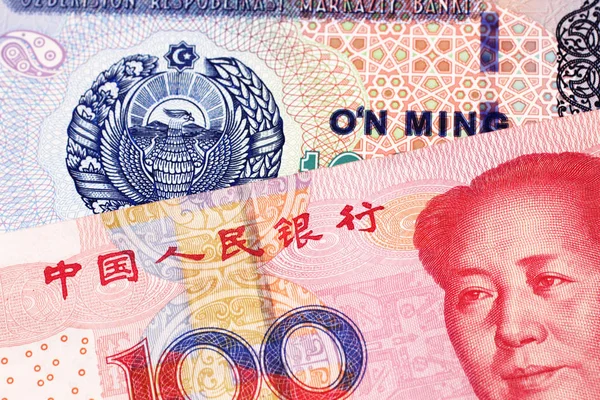 A 10000 som note from Uzbekistan, close up in macro with a 100 yuan bank note from the People\'s Republic of China featuring Mao Tse Tung