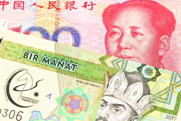 A green one manat note from Turkmenistan close up in macro with a red, one hundred yuan renminbi bank note from the People\'s Republic of China