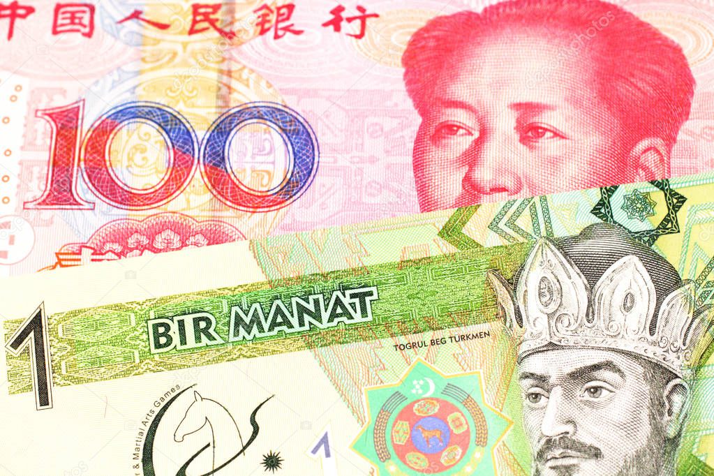 A green one manat note from Turkmenistan close up in macro with a red, one hundred yuan renminbi bank note from the People's Republic of China