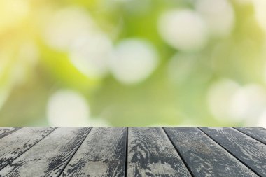 Yaprak yeşil bokeh arka plan ile eski ahşap zemin.