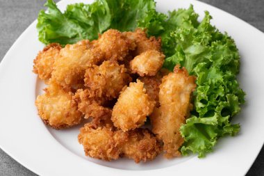 Kızarmış tavuk ve masada beyaz çanak marul.