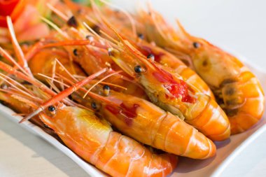 Izgara karides, yanık karides taş masanın üzerine beyaz plaka.