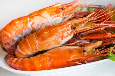 Izgara karides, yanık karides taş masanın üzerine beyaz plaka.