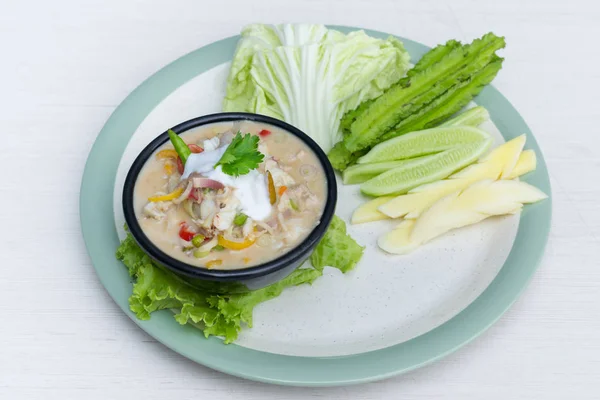 Crab dip with coconut milk and vegetables in bowl.