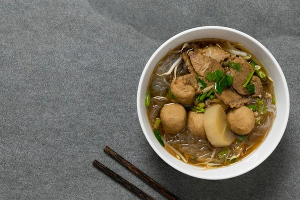Vermicelli, beton masada beyaz kasede sığır eti..