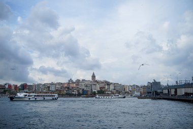 Istanbul, Türkiye - 26 Mayıs 2018: Akşam görünümü Galata Kulesi yer, insanlar Balık tutma ile Köprü ve boğaz deniz suyu tekneler, martılar ve bulutlu gökyüzü arka plan, Istanbul