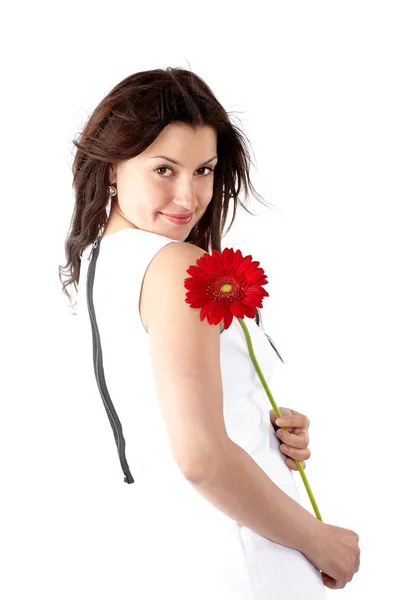 Belle jeune femme en robe blanche, posant latéralement avec une fleur rouge et regardant la caméra — Photo