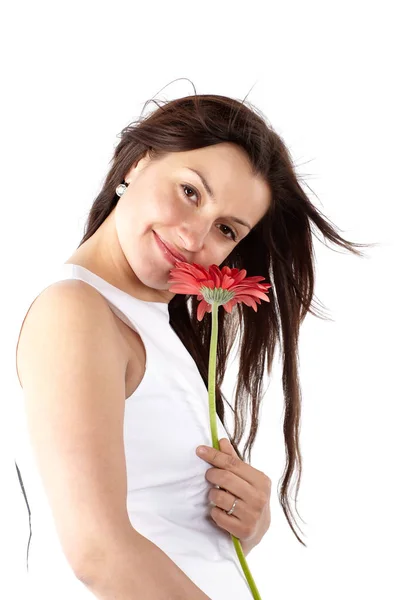 Belle jeune femme en robe blanche, posant latéralement avec une fleur rouge, regardant la caméra et souriant — Photo