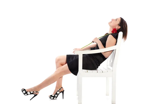 Heureuse femme sexy assise sur une chaise en bois avec fleur de gerbera et rêvant de week-end — Photo