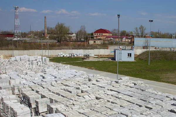 Many packages of autoclaved aerated concrete on pallets put one on the other on an outdoor factory warehouse. Top view of industrial area.