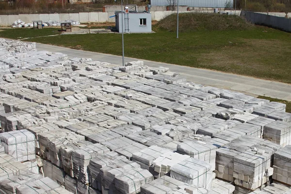 Many packages of autoclaved aerated concrete on pallets put one on the other on an outdoor factory warehouse. Top view of industrial area.