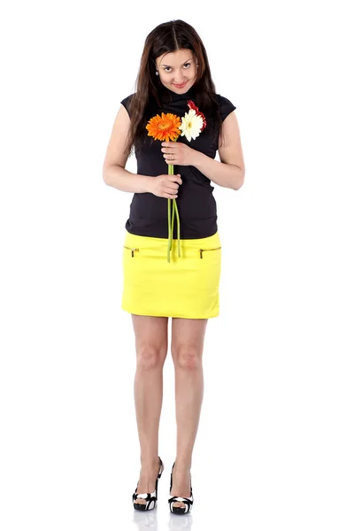 Jeune femme en jupe courte jaune avec gerberas, corps entier, inclinant la tête vers l'avant — Photo