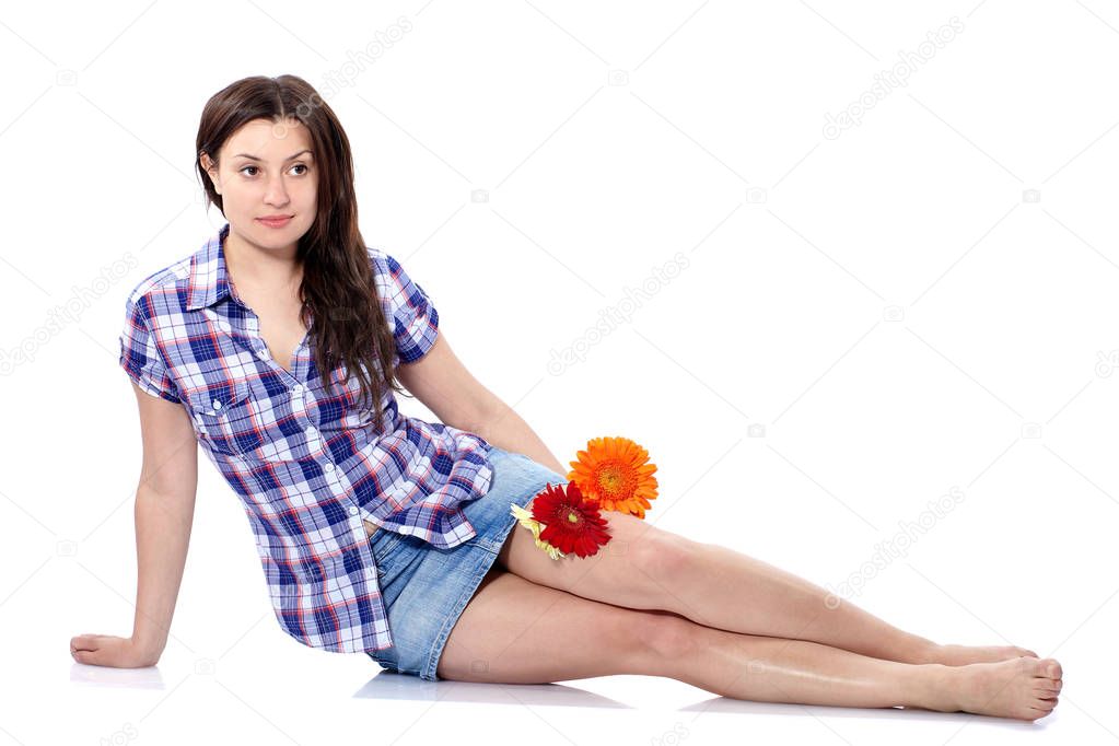 Beautiful young woman in plaid shirt sitting on the floor with gerberas