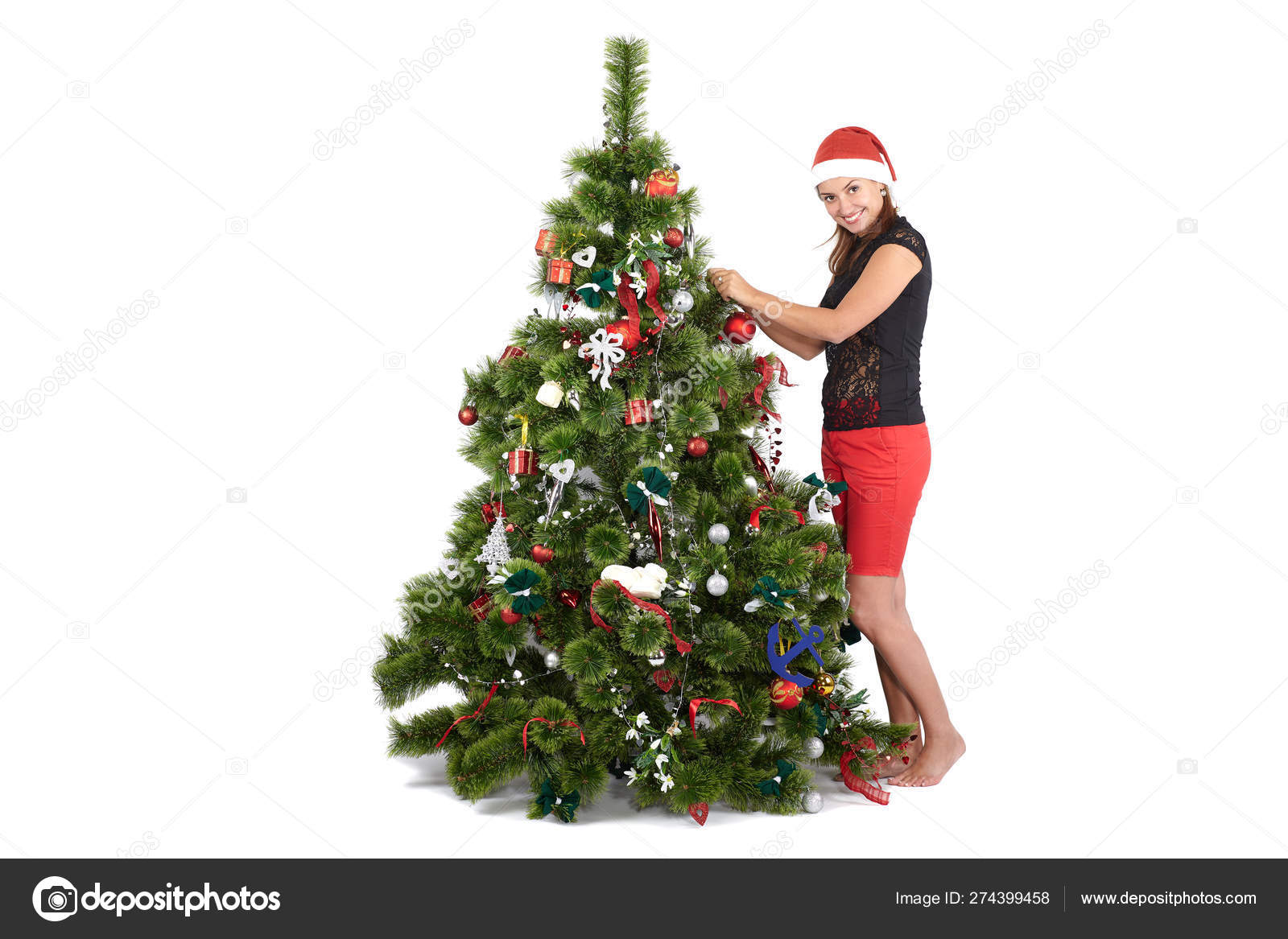 Beautiful Smiling Woman In Santa Cap Decorating Christmas Tree On