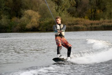 Moskova, Rusya - 28 Eylül 2008: Wakeboard binicisi şehir nehrinde beleşe binme numaraları ve becerileri gösteriyor. Motorlu teknenin arkasındaki Wakeboardcu.