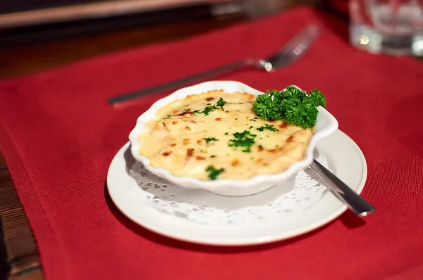 Casserole with a golden crust, mushroom julienne with baked cheese, creamy gratin. Delicious julienne with cheese in clay pot with greenery. Julienne in white bowl with herbs. — Stock Image Casserole Golden Crust Mushroom Julienne Baked Cheese Creamy Gratin Delicious Stock Picture