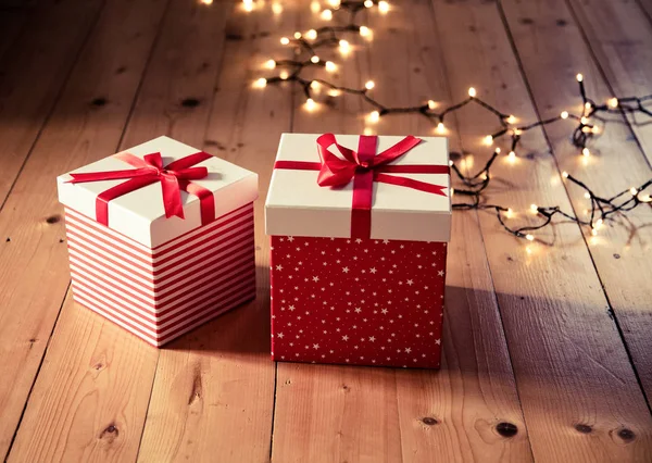 Rote Geschenkboxen Und Weihnachtsbeleuchtung Auf Holzboden — Stockfoto