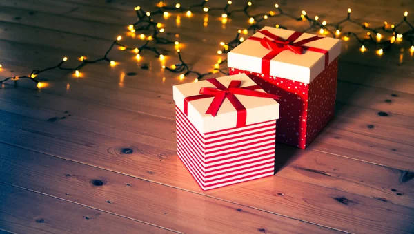 Rote Geschenkboxen Und Weihnachtsbeleuchtung Auf Holzboden — Stockfoto