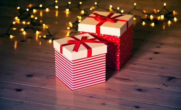 Rote Geschenkboxen Und Weihnachtsbeleuchtung Auf Holzboden — Stockfoto