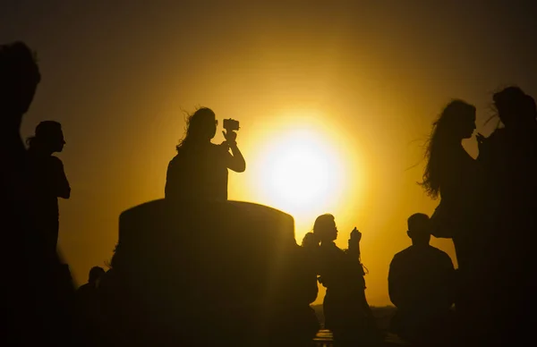 silhouettes of people taking pictures with smartphones