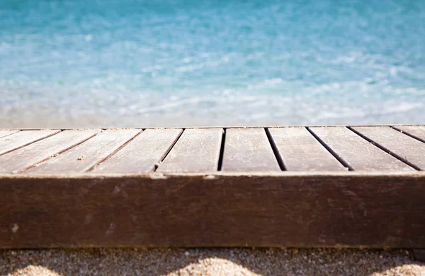 Tablón de madera en arena y mar azul en el fondo —  Fotos de Stock