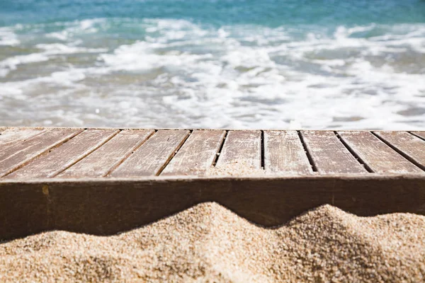 Wooden plank in sand and blue sea in the background — Stock Photo, Image