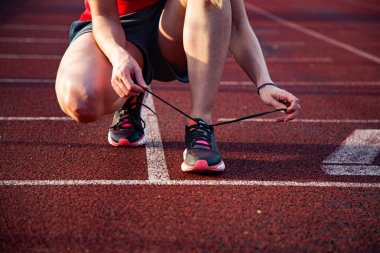 koşu pistinde genç kadın ayakkabılarını bağlayarak