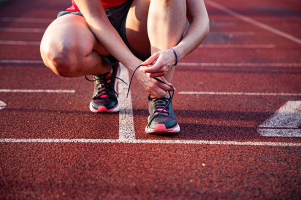 koşu pistinde genç kadın ayakkabılarını bağlayarak