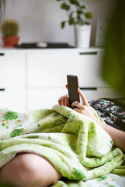 Kvinna med en smartphone i sängen — Stockfoto