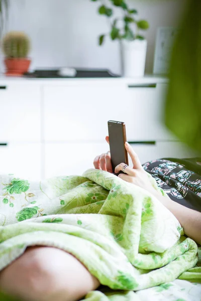 Mulher usando um smartphone na cama — Fotografia de Stock