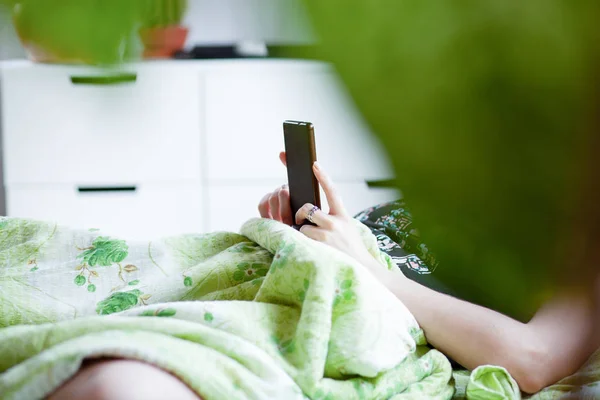 Mulher usando um smartphone na cama — Fotografia de Stock