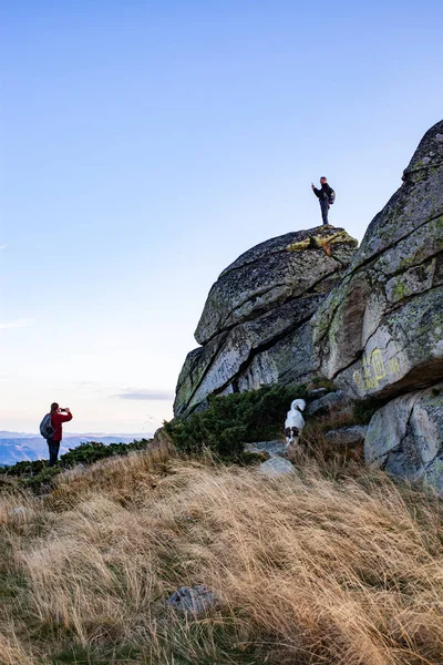 岩の上に座っている間に写真を撮るハイカーカップル — ストック写真